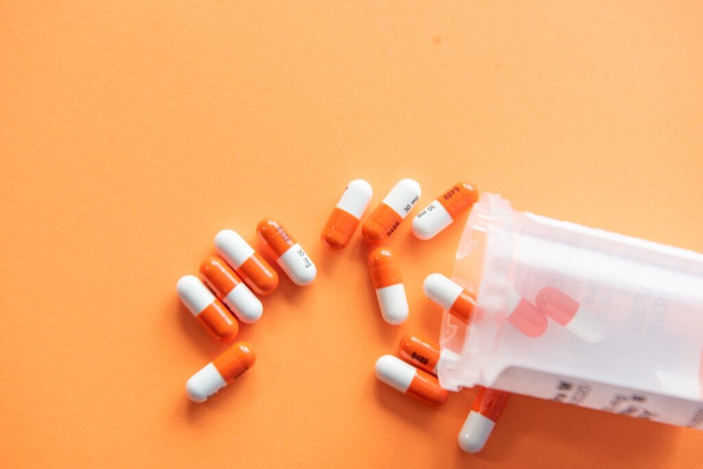 Prescription drugs on an orange background with a pill bottle. Orange pills.